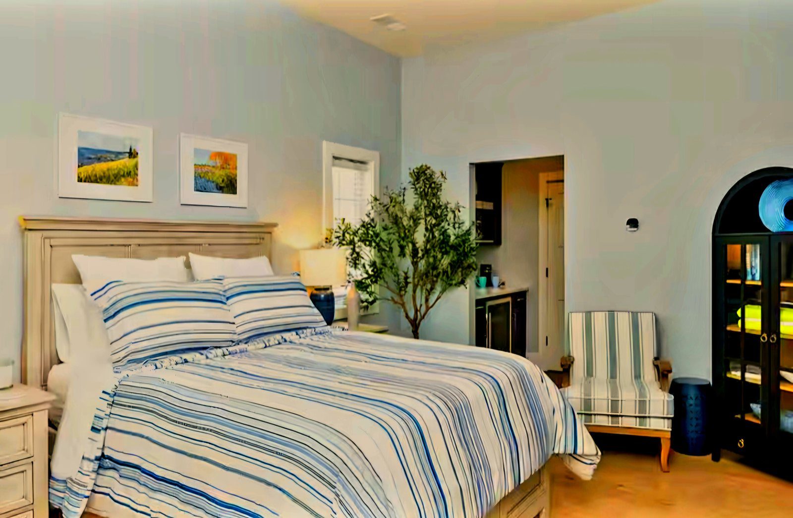 Queen Suite interior with bed, armchair, and kitchenette entryway